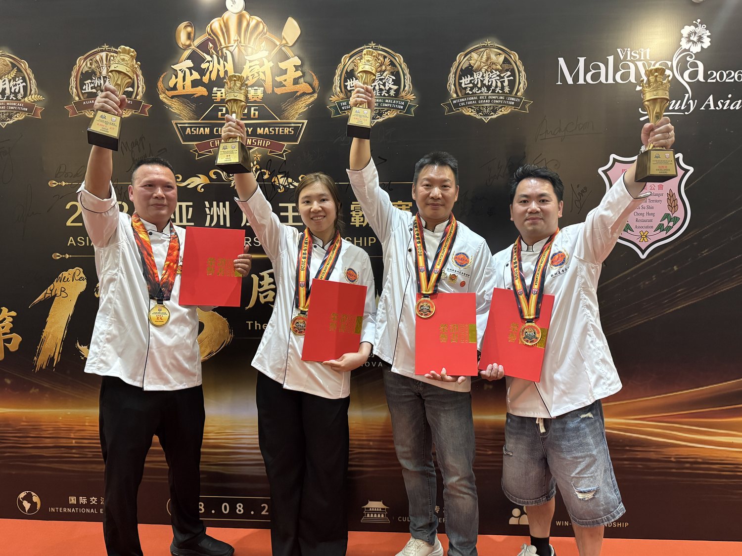 Vier chefs houden hun bekers en oorkondes omhoog voor de backdrop van de Asian Culinary Masters Championship 2026